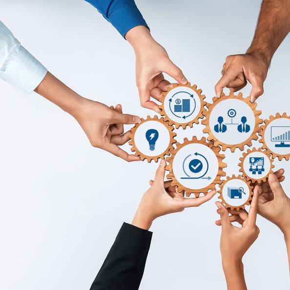 Diverse Hands Collaborating with Gears and Icons Symbolizing Teamwork, Technology, and Business Strategy in a Modern Office Context. Amity